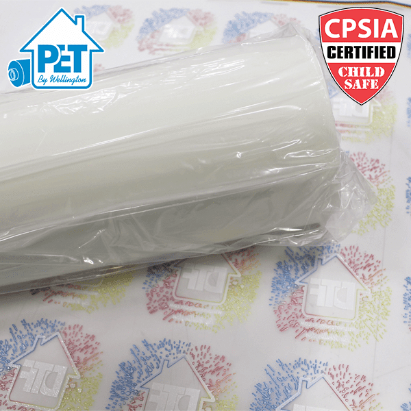 Película de Transferencia HousePET Picture of a roll of PET film on top of a sheet of DTF transfers